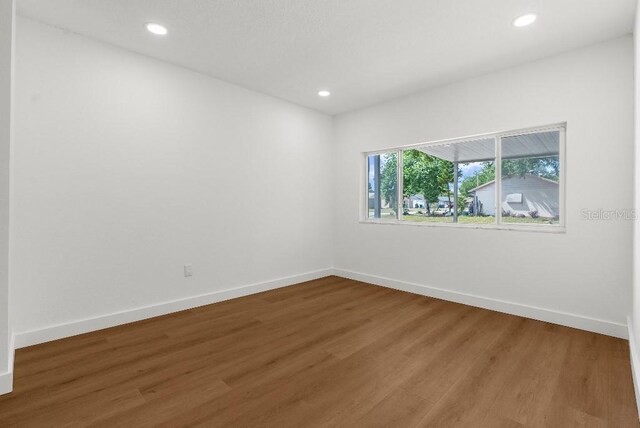empty room featuring recessed lighting, baseboards, and wood finished floors