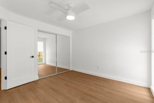 unfurnished bedroom with a ceiling fan, baseboards, wood finished floors, and a closet