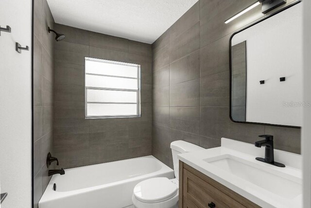 bathroom with toilet, tile walls, bathing tub / shower combination, and vanity