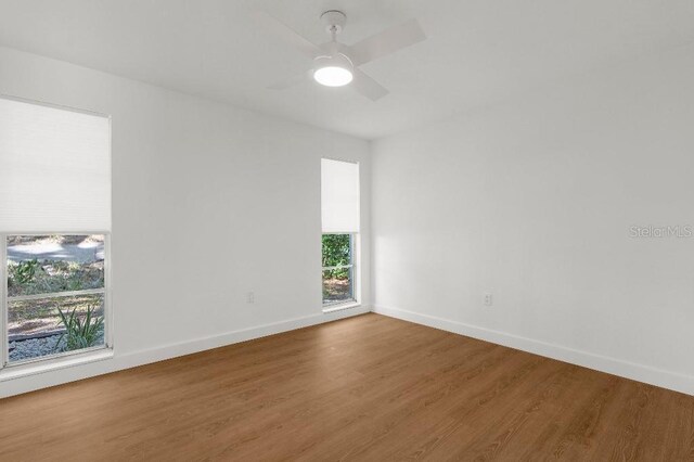 empty room with baseboards, a ceiling fan, and wood finished floors