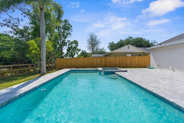 view of swimming pool featuring a pool with connected hot tub, a fenced backyard, and a patio area