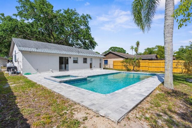view of pool with a patio, a fenced backyard, and a pool with connected hot tub