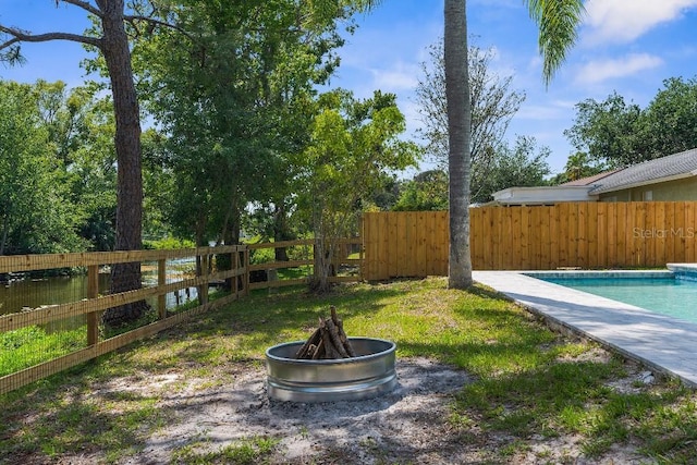 view of yard with a fenced in pool, a fenced backyard, and an outdoor fire pit