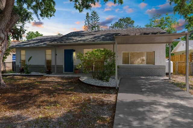 view of front of house with fence, stucco siding, roof with shingles, and brick siding