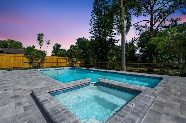 view of pool featuring a patio, a fenced backyard, and a pool with connected hot tub
