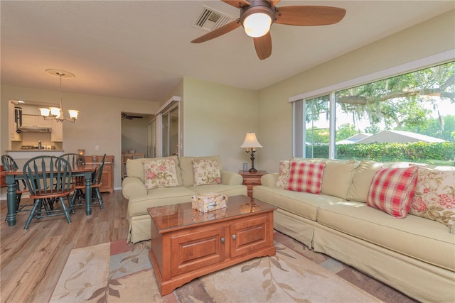 living area with light wood-style floors, a chandelier, and ceiling fan