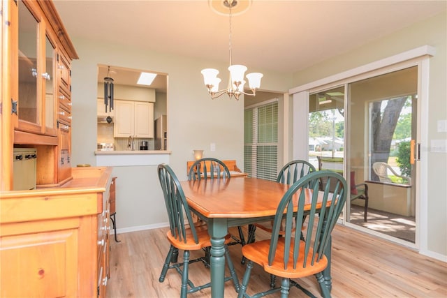 dining space featuring light wood-style floors, a chandelier, and baseboards