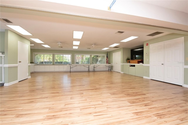 empty room with light wood-type flooring, a skylight, and a ceiling fan