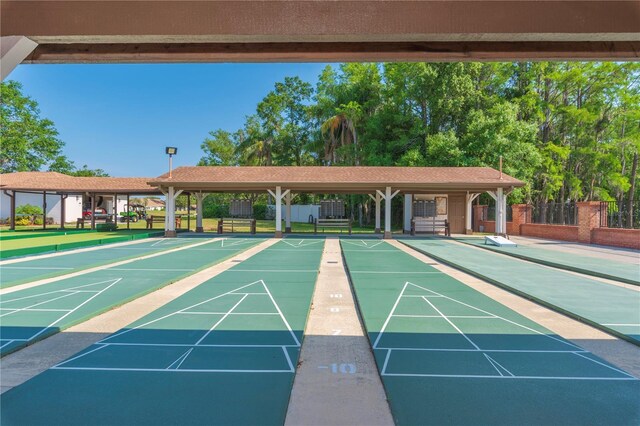 view of property's community featuring fence and shuffleboard