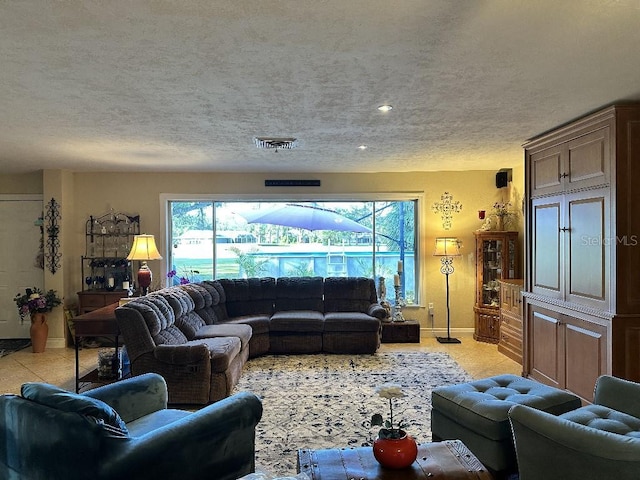 living room featuring visible vents, a textured ceiling, baseboards, and a healthy amount of sunlight