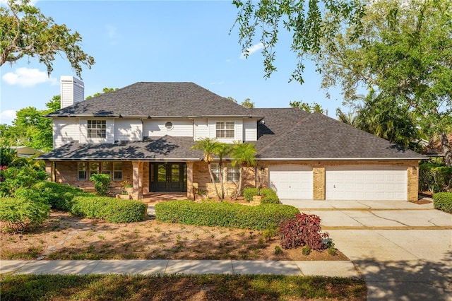 101 Ponce De Leon Blvd, Belleair, FL 33756 - view of front of home featuring a chimney, driveway, brick siding, french doors, and a garage