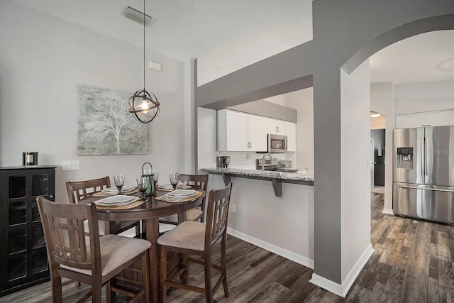 dining area featuring arched walkways, baseboards, visible vents, and dark wood finished floors