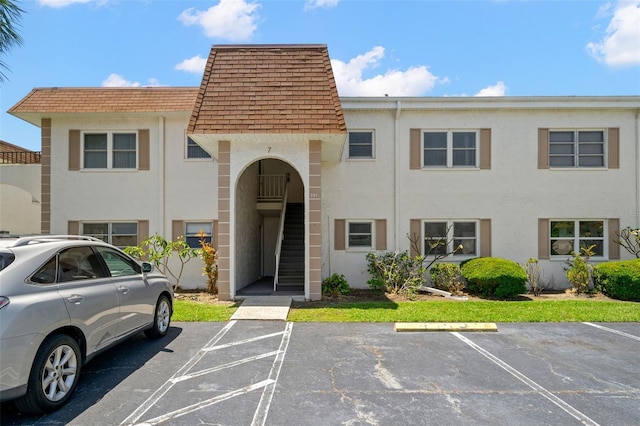381 S Mcmullen Booth Rd Unit 72, Clearwater, FL 33759 - view of front of home featuring uncovered parking, mansard roof, a shingled roof, and stucco siding