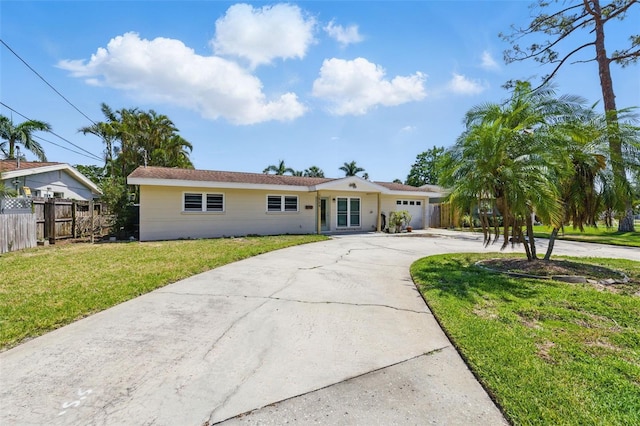 ranch-style house featuring fence, curved driveway, an attached garage, and a front lawn