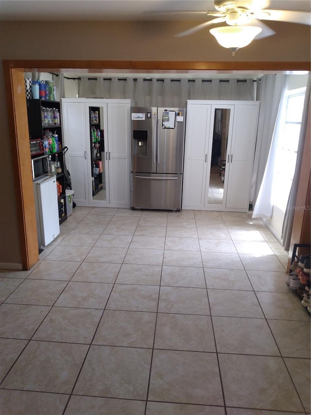 kitchen featuring white cabinetry, ceiling fan, stainless steel fridge, and light tile patterned floors