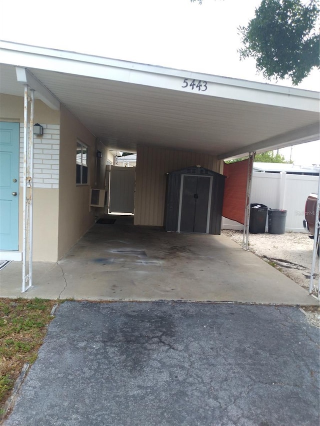 view of parking / parking lot with fence and an attached carport