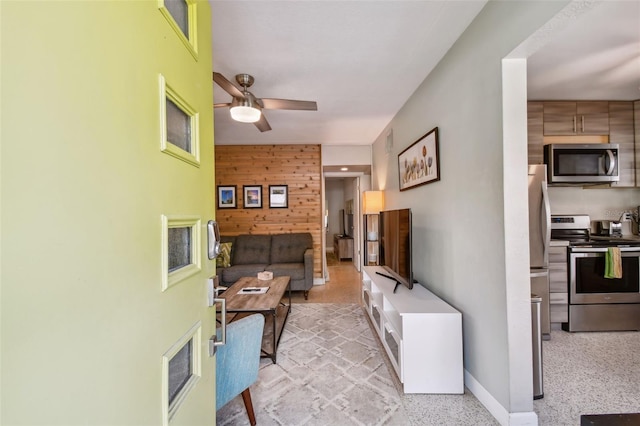 3626 17th St N, Saint Petersburg, FL 33713 - living room featuring wooden walls, baseboards, a ceiling fan, and light speckled floor