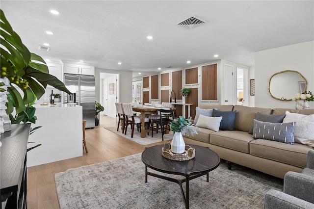 living room with light wood-style floors, recessed lighting, and visible vents