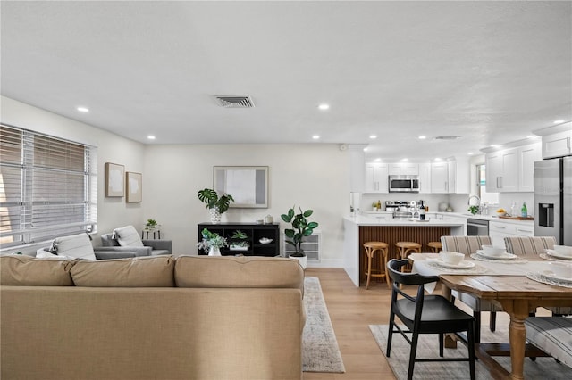 living room with recessed lighting, visible vents, and light wood-type flooring