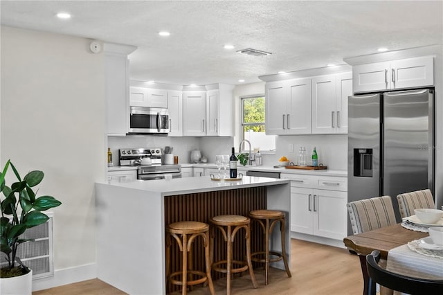 kitchen featuring white cabinets, appliances with stainless steel finishes, visible vents, and light wood-type flooring
