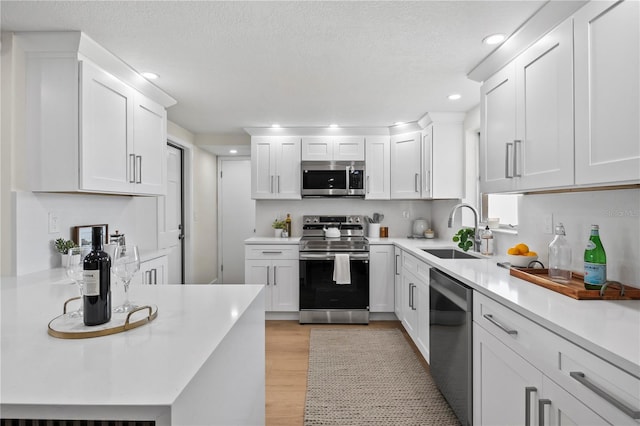 kitchen featuring light countertops, stainless steel appliances, white cabinets, and a sink