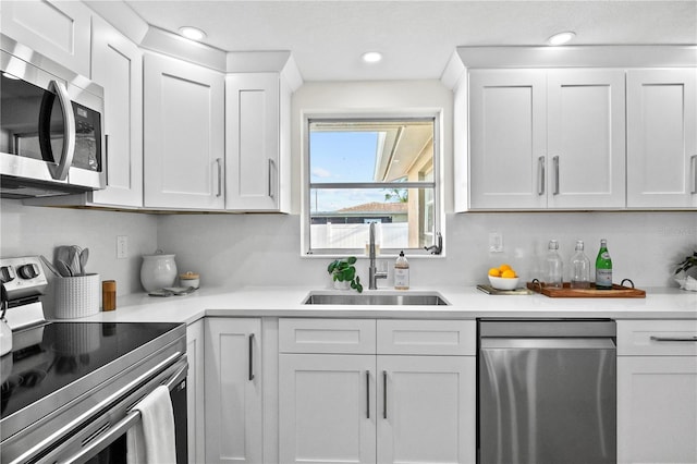 kitchen with white cabinets, a sink, light countertops, stainless steel appliances, and recessed lighting