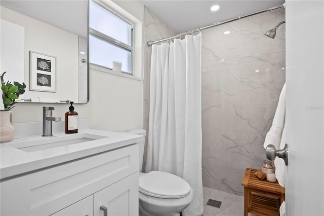bathroom with vanity, a tile shower, and toilet