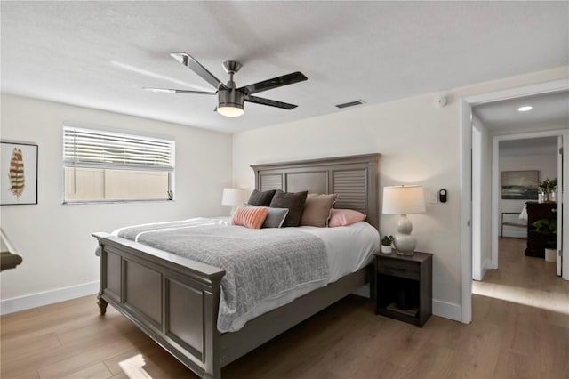 bedroom featuring baseboards, visible vents, ceiling fan, and light wood-style floors