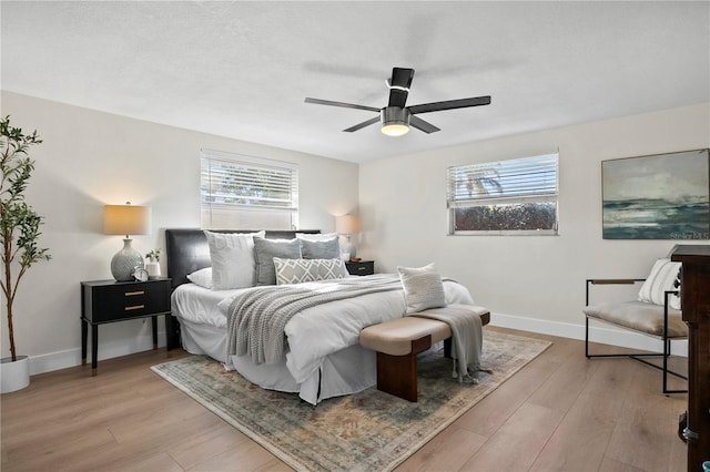 bedroom with baseboards, a ceiling fan, and light wood-style flooring