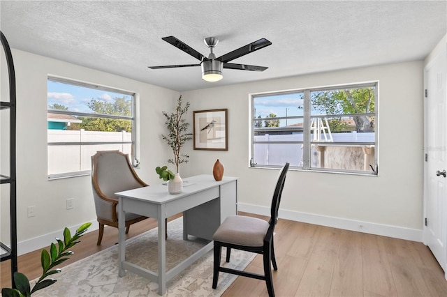 home office featuring baseboards, a ceiling fan, and light wood-type flooring