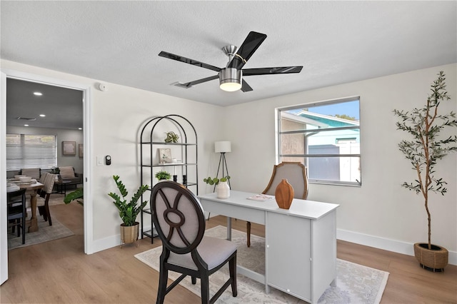office area featuring a ceiling fan, baseboards, a textured ceiling, and light wood-style floors
