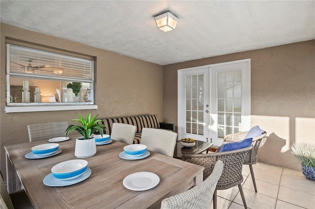 dining area with a textured wall, french doors, and tile patterned flooring