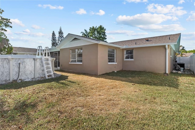 back of house with a yard, fence, and stucco siding