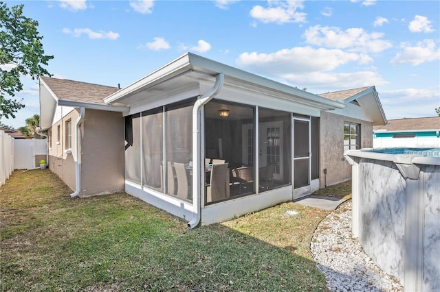 rear view of property featuring a yard, roof with shingles, fence, and a sunroom