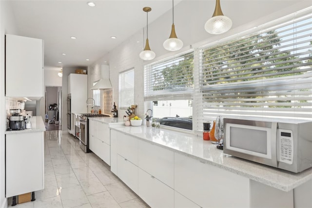 757 32nd Ave N, Saint Petersburg, FL 33704 - kitchen featuring marble finish floor, white microwave, gas range, and white cabinetry