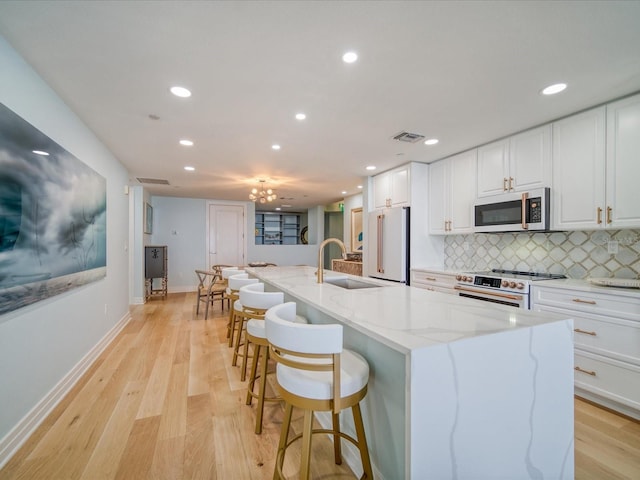 331 Cleveland St # 1806, Clearwater, FL 33755 - kitchen with visible vents, high end appliances, white cabinetry, a sink, and light wood-style flooring