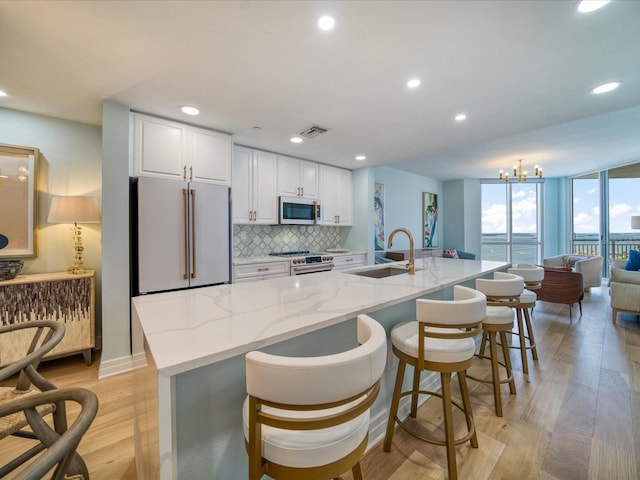 331 Cleveland St # 1806, Clearwater, FL 33755 - kitchen featuring decorative backsplash, visible vents, high end appliances, a sink, and white cabinetry