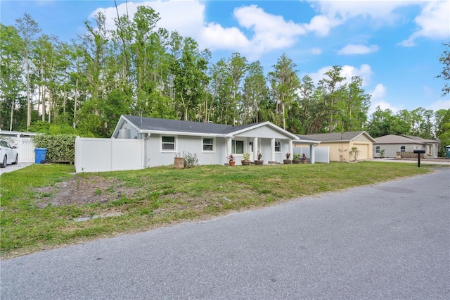 view of front of house featuring a garage, a front lawn, fence, and covered porch