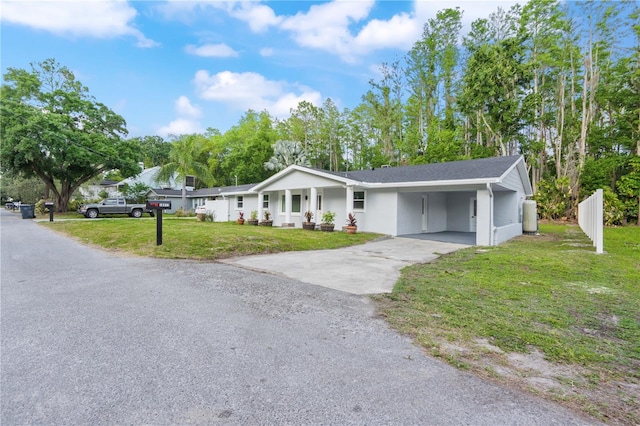 ranch-style house featuring a porch, a front yard, an attached carport, concrete driveway, and stucco siding
