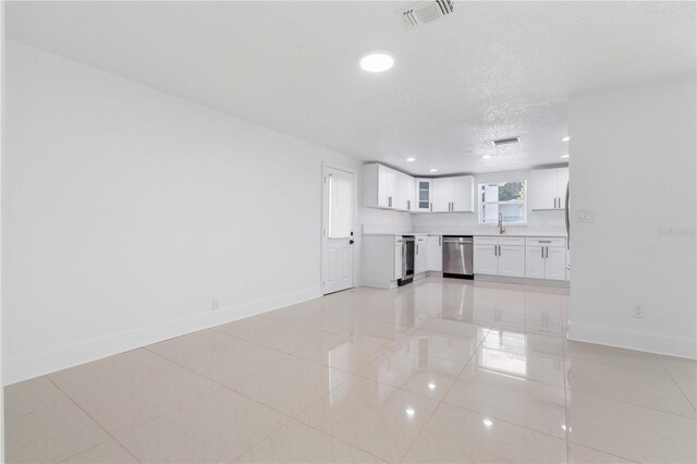 unfurnished living room with light tile patterned flooring, a sink, beverage cooler, baseboards, and visible vents