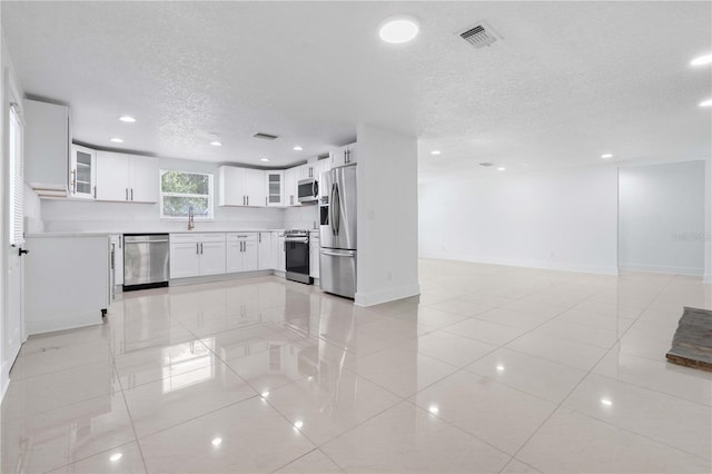 kitchen with visible vents, open floor plan, a textured ceiling, a sink, and stainless steel appliances