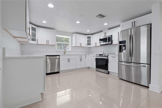 kitchen featuring a sink, stainless steel appliances, recessed lighting, visible vents, and glass insert cabinets