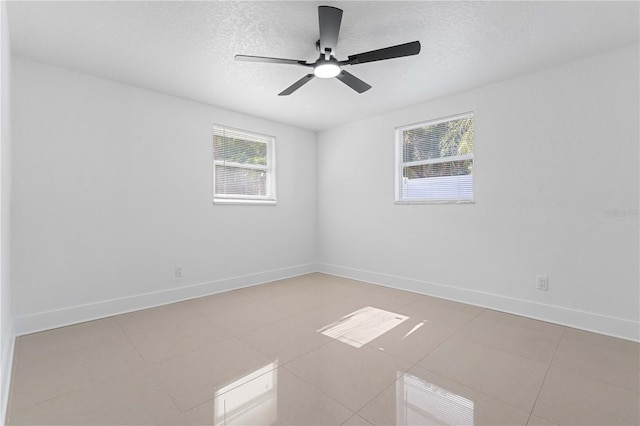 unfurnished room featuring a ceiling fan, baseboards, light tile patterned flooring, and a textured ceiling