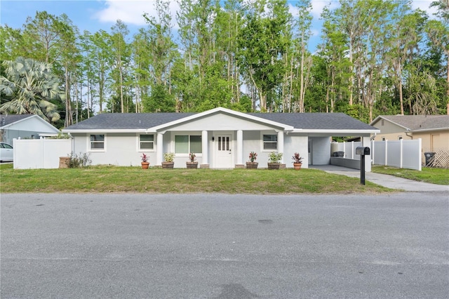 single story home with fence, a carport, concrete driveway, and a front lawn
