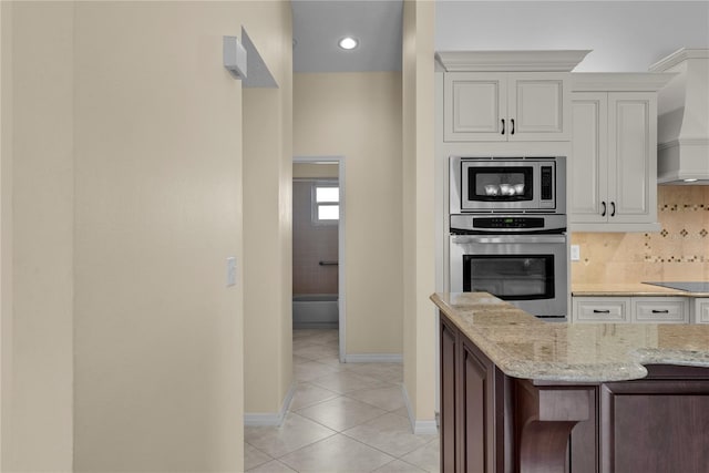5290 White Sand Cir NE, Saint Petersburg, FL 33703 - kitchen featuring stainless steel appliances, custom range hood, light tile patterned flooring, light stone counters, and baseboards