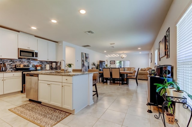 kitchen featuring visible vents, light tile patterned flooring, open floor plan, backsplash, and stainless steel appliances
