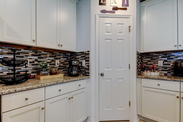 kitchen featuring light stone counters, decorative backsplash, and white cabinets