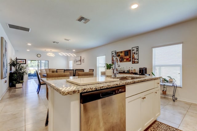 kitchen featuring a kitchen island with sink, dishwasher, a sink, light tile patterned floors, and open floor plan