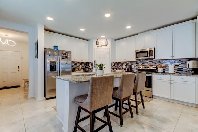 kitchen with light tile patterned floors, appliances with stainless steel finishes, a breakfast bar, and backsplash