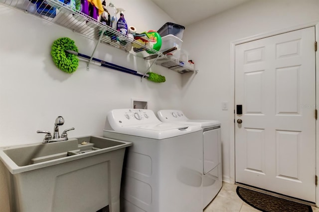 laundry area featuring light tile patterned floors, laundry area, washing machine and dryer, and a sink
